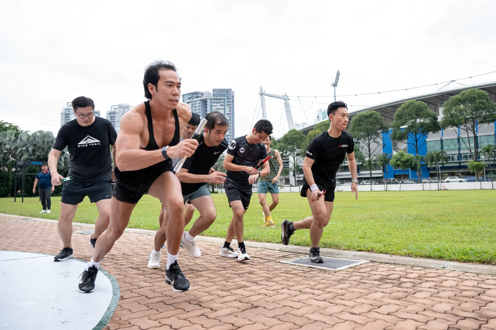 Well-timed action of a sprint start at an outdoor fitness event, all subjects sharp mid-stride with stadium skyline context