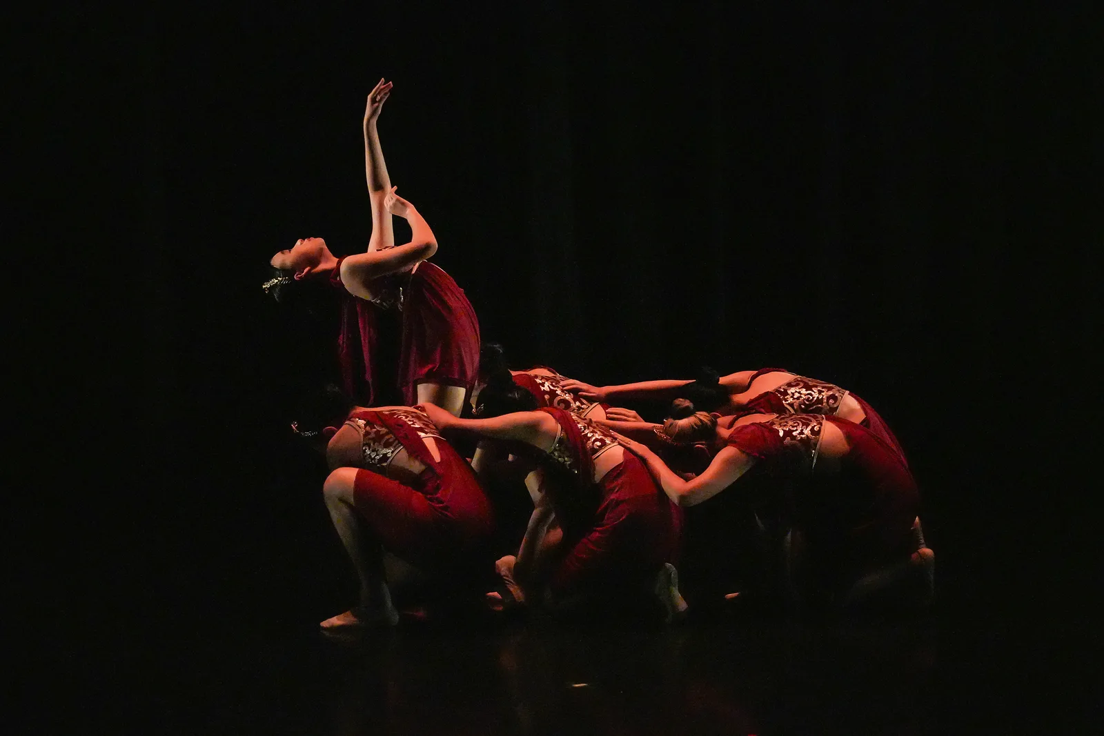 Contemporary dance on a black stage, red-lit cluster with one raised arm — dramatic, cinematic, exactly the dark RS aesthetic