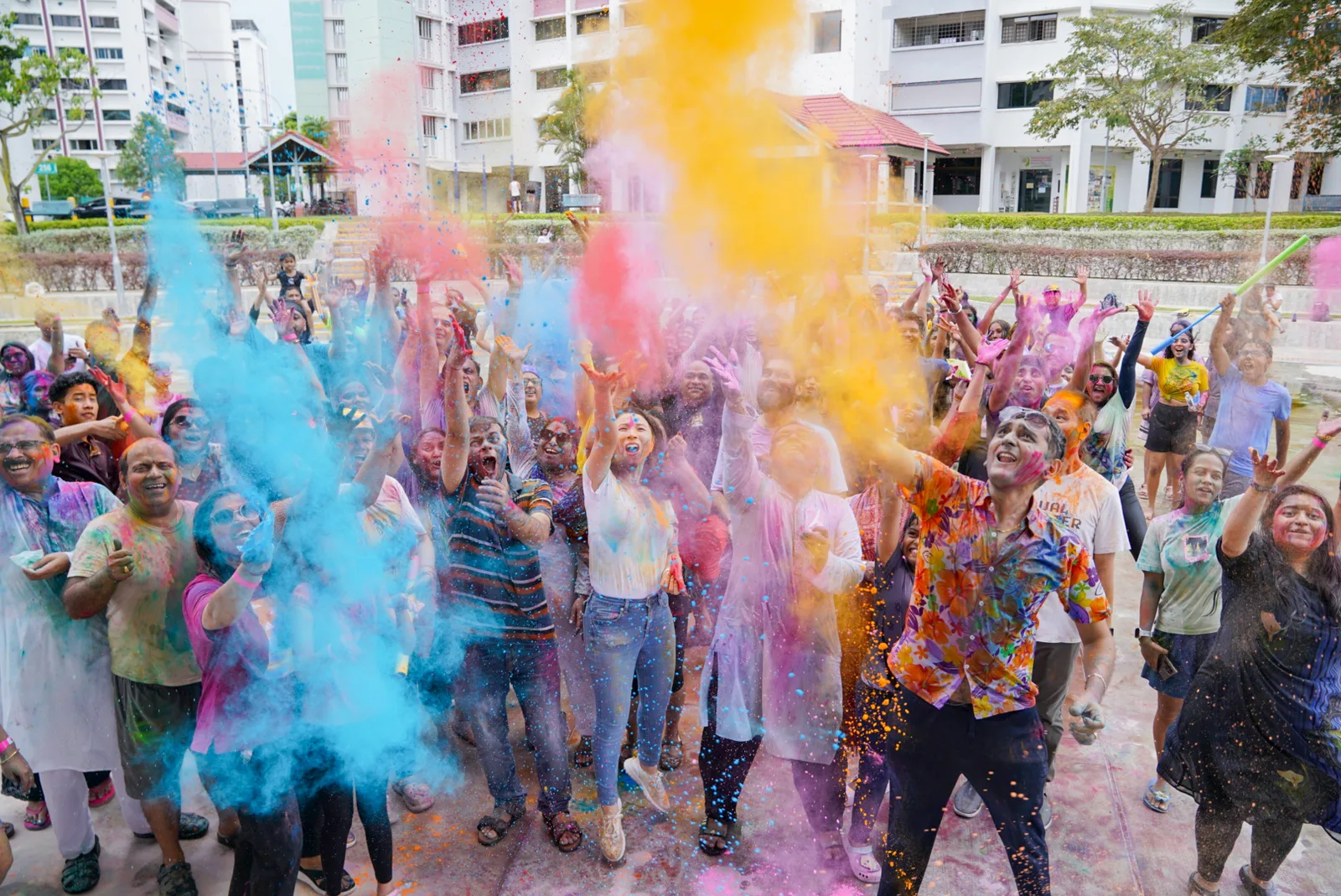 Holi colour-throw crowd with blue/orange powder mid-air — genuine great energy and timing