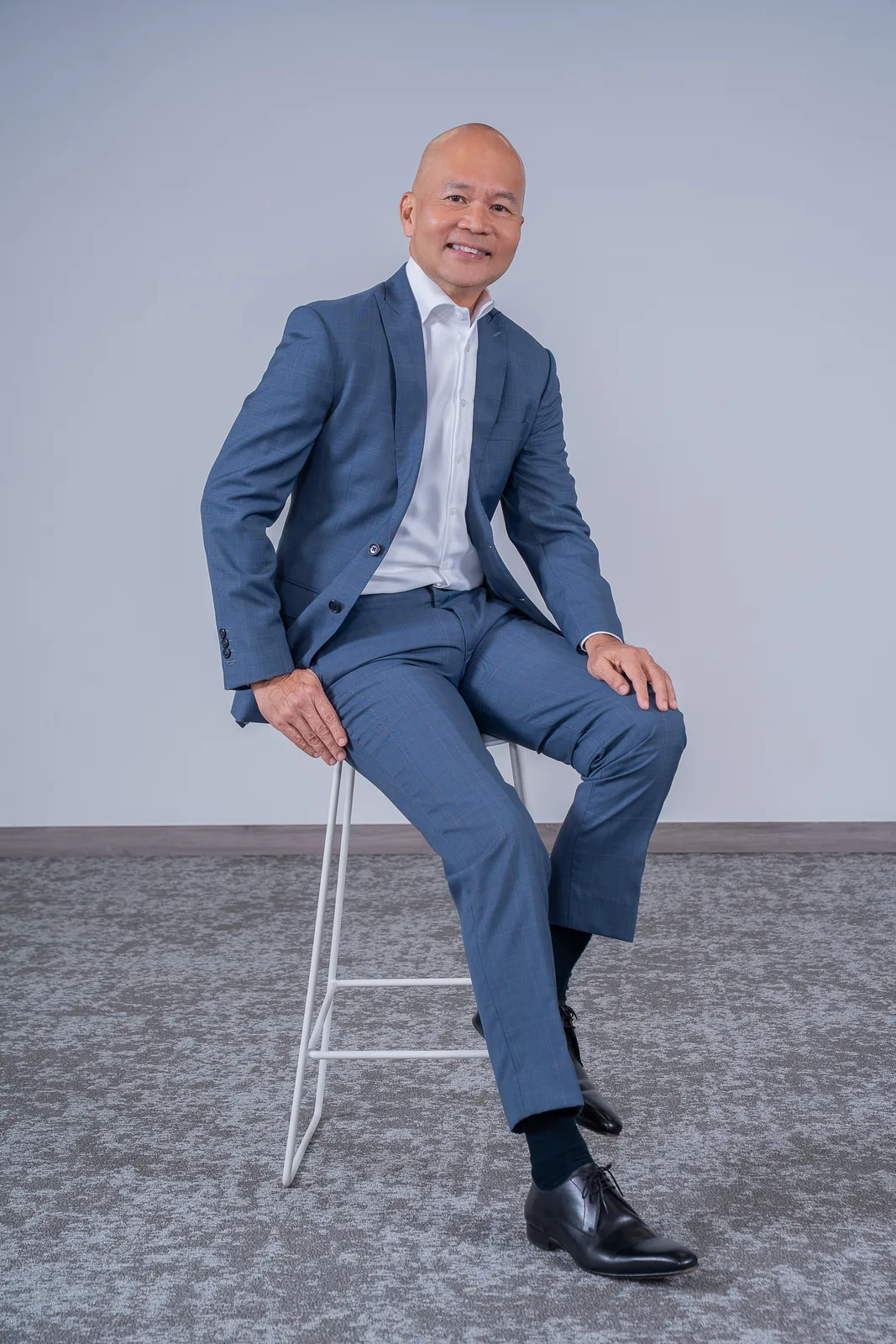 Polished full-length executive portrait on grey seamless; corporate relevance, clean light and posing, though a touch generic for he