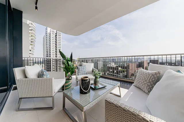 Outdoor rattan furniture, cushions and homeware arranged on a high-rise apartment balcony