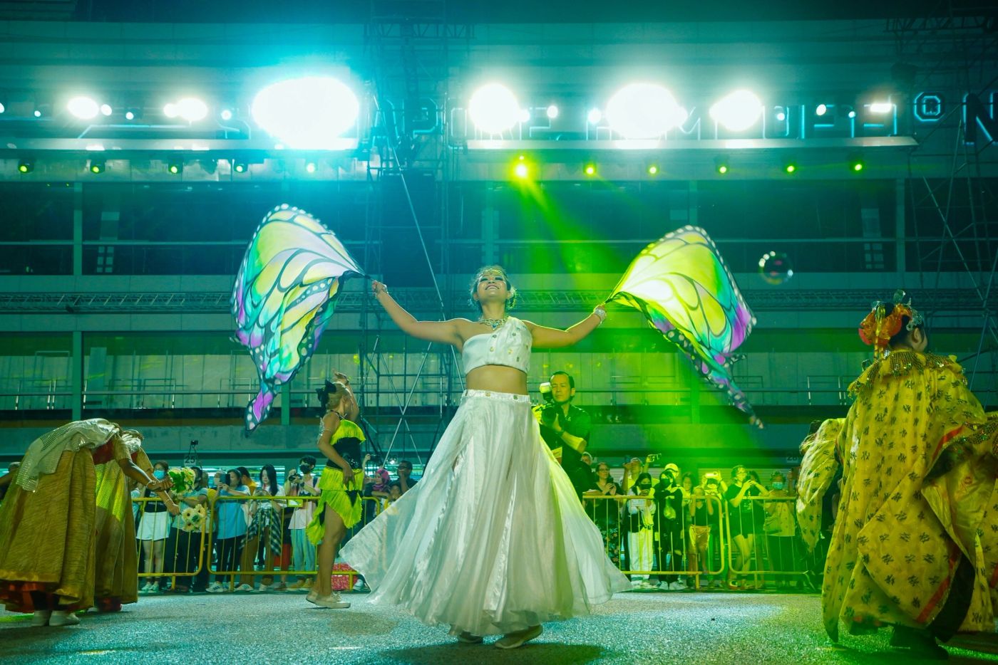 Dancer in white with butterfly wings under green stage light