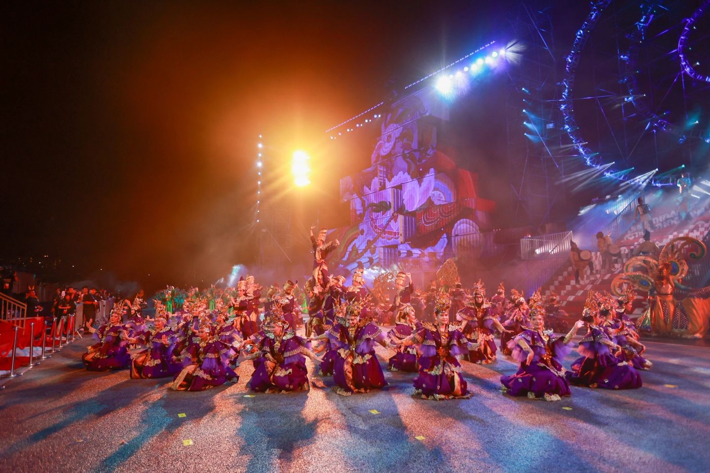 Seated mass dance formation lit in warm orange