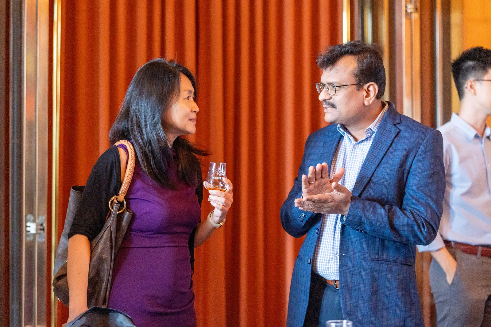Guests networking against warm drapes and wood panelling in a hotel ballroom — RS Photography